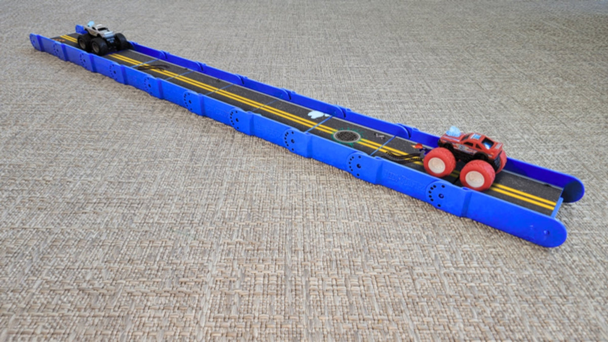Long straight bright blue Redi-Rampz track with two monster trucks